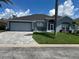 Single-story home with gray exterior, paved driveway, and lush landscaping at 148 Joewood Trl, Davenport, FL 33837