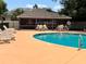 Community pool with lounge chairs, and a screened in pool house with tables and chairs for residents at 148 Joewood Trl, Davenport, FL 33837