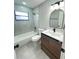 Bathroom with tub, toilet, wood vanity, and gray tile at 202 Cobalt Dr, Kissimmee, FL 34758