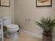 A half bathroom featuring a toilet, tiled floors and a large plant as decor at 2717 Coupe St, Kissimmee, FL 34746