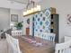 Casual dining room with wooden table, white chairs, and a lovely quilt hanging on the wall at 296 Del Sol Ave, Davenport, FL 33837