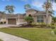 Tan one-story house with brown garage door, landscaping, and palm trees at 296 Del Sol Ave, Davenport, FL 33837