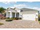 White single-story house with a paver driveway and palm trees at 2937 Bella Flore Ter, New Smyrna Beach, FL 32168