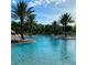 Large community pool with palm trees, lounge chairs and blue skies in a tropical paradise setting at 2937 Bella Flore Ter, New Smyrna Beach, FL 32168