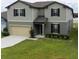 Two-story home featuring neutral siding, black shutters, a well-maintained lawn, and an attached two-car garage at 446 Citrus Isle Loop, Davenport, FL 33837