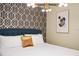 King-size bed with geometric wallpaper and a mid-century modern chandelier at 4575 Narrative Ln, Kissimmee, FL 34746