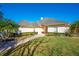 Tan house with a red door, palm trees, and a brick walkway at 5666 Merlin Way, St Cloud, FL 34772