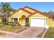 Beautiful yellow house with a tile roof, white garage door, and well-manicured lawn at 154 Robin Rd, Davenport, FL 33896