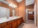 Bathroom featuring double sinks, wood cabinets, a large mirror, and a glass door shower at 2615 Pawnall St, Kissimmee, FL 34747