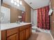 Bathroom featuring a sink with wood cabinets, a large mirror, and a shower with a red curtain at 2615 Pawnall St, Kissimmee, FL 34747
