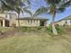 Rear exterior view of the house with a well-maintained yard, tropical landscaping, and a patio at 6826 Goldflower Ave, Harmony, FL 34773