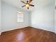 Cozy bedroom with wood floors, ceiling fan, and a window providing natural light at 6826 Goldflower Ave, Harmony, FL 34773
