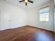 Bedroom featuring wood floors, a ceiling fan, window, and a door leading to the hallway at 6826 Goldflower Ave, Harmony, FL 34773