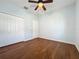 Bedroom featuring wood floors, ceiling fan, double door closet, and ample space at 6826 Goldflower Ave, Harmony, FL 34773