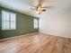 Bedroom featuring wood floors, a ceiling fan and an accent wall with bright windows at 6826 Goldflower Ave, Harmony, FL 34773