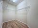 Walk-in closet featuring wood floors and built in shelving at 6826 Goldflower Ave, Harmony, FL 34773