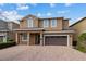 Two-story house with brown exterior, a three-car garage, and a paved driveway at 7617 Wilmington Loop, Kissimmee, FL 34747