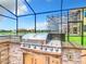 Outdoor kitchen with grill, sink, and granite countertop at 870 Spinnaker Way, Kissimmee, FL 34746