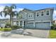 Two-story house with gray siding, three-car garage, and landscaped yard at 8870 Backspin Ln, Champions Gate, FL 33896