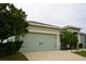 Two-car garage with light green doors and landscaping at 1028 Merrimack Blvd, Davenport, FL 33837