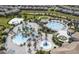 Aerial view of community pool area with various pools, a water slide, and a sandy beach volleyball court at 1138 Kingsbarn St, Davenport, FL 33896
