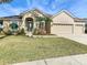 Tan house with brown roof, three-car garage, and landscaped yard at 125 Viola Dr, Auburndale, FL 33823