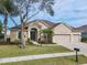 Tan house with brown roof, three-car garage, and landscaped yard at 125 Viola Dr, Auburndale, FL 33823