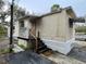 Tan mobile home with a covered porch and wooden steps at 215 4Th St, Orlando, FL 32824