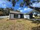 Single-story house with freshly painted white and dark gray exterior, showcasing a teal front door at 7450 Crooked Lake Cir, Orlando, FL 32818