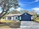 Newly renovated single-story home featuring a teal front door and a navy blue garage door at 7450 Crooked Lake Cir, Orlando, FL 32818