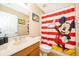 Charming bathroom with Mickey Mouse themed shower curtain and coordinating decor for a fun touch at 7588 Assembly Ln, Reunion, FL 34747