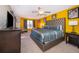 Bright main bedroom with yellow walls, stylish furniture, and a large bed with an upholstered headboard at 7588 Assembly Ln, Reunion, FL 34747