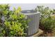 Grey AC unit is nestled among green bushes at 1280 Tupelo Trl, Haines City, FL 33844