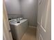 Bright laundry room with a white washer and dryer unit and wire shelving above for storage at 143 Glasgow Ct, Davenport, FL 33897