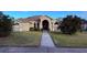 Tan house with a walkway leading to the front door, lush landscaping and a neatly kept lawn at 1534 Gants Cir, Kissimmee, FL 34744