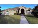 Tan house with a walkway leading to the front door, lush landscaping and a neatly kept lawn at 1534 Gants Cir, Kissimmee, FL 34744