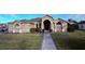 Tan house with a walkway leading to the front door, lush landscaping and a neatly kept lawn at 1534 Gants Cir, Kissimmee, FL 34744