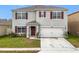 Inviting two-story home with red shutters, a manicured lawn, and a convenient two-car garage at 1634 Reddish Egret Ct, Davenport, FL 33897