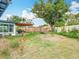 Large backyard with a covered patio, dining table, lush greenery, and a tall mature tree at 420 Sunrise Dr, Orlando, FL 32803