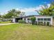 Well-kept home exterior features a modern design with a carport, inviting greenery, and a bright orange door at 420 Sunrise Dr, Orlando, FL 32803