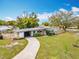 Charming single-story home with a long driveway, well-manicured lawn, and a modern orange front door at 420 Sunrise Dr, Orlando, FL 32803