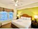 King bed with ceiling fan and views from large windows at 8100 Poinciana Blvd # 2405, Orlando, FL 32821