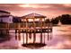 Scenic view of a gazebo on a lake with a fountain, reflecting a colorful sunset on the water at 122 Macaulays Cv, Haines City, FL 33844