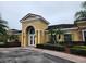 Clubhouse exterior featuring stucco siding, terra cotta roof, well manicured shrubbery, and tropical palm trees at 3459 Allegra Cir, St Cloud, FL 34772