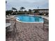 Community pool surrounded by tables, chairs, and lounge seating, all enclosed by a black metal fence at 3459 Allegra Cir, St Cloud, FL 34772