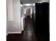Hallway leading to the kitchen, showcasing dark wood floors and a stacked washer dryer at 4575 S Texas Ave # 207, Orlando, FL 32839