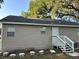 Rear view of house showcasing a tan exterior, white steps, and landscaping at 5920 Nw 65Th St, Ocala, FL 34482
