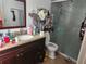 Bathroom with a brown vanity, sink, toilet, and a glass-enclosed shower at 602 Caddy Dr, Kissimmee, FL 34759
