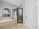 Bathroom features a soaking tub, tiled shower, and arched window with a scenic view at 733 Desert Mountain Ct, Reunion, FL 34747