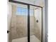 Modern shower with tan tiles and a black framed shower door, complemented by a window at 733 Desert Mountain Ct, Reunion, FL 34747